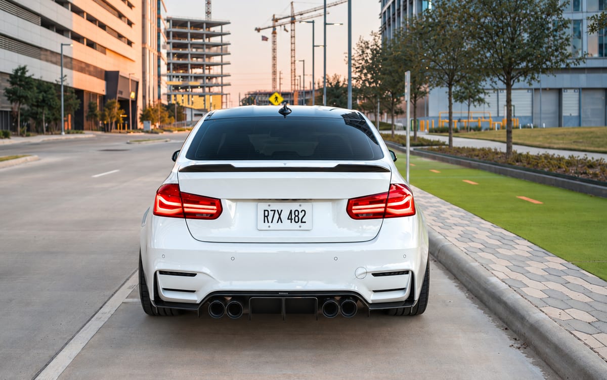 Rear view of a white sedan on a city street with construction buildings in the background.